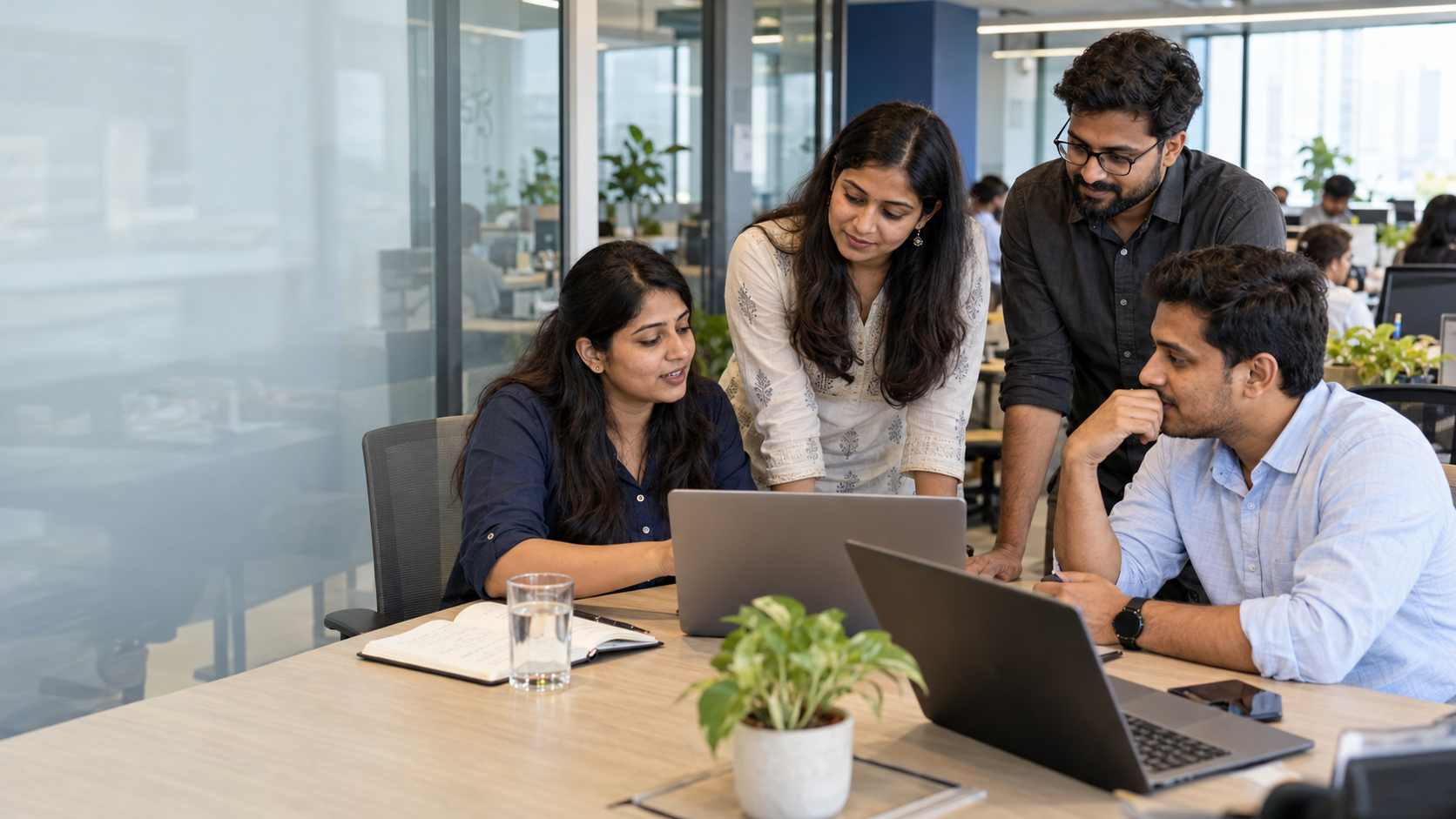 Four FrenzoFinserv team members collaborating around a laptop in the office
